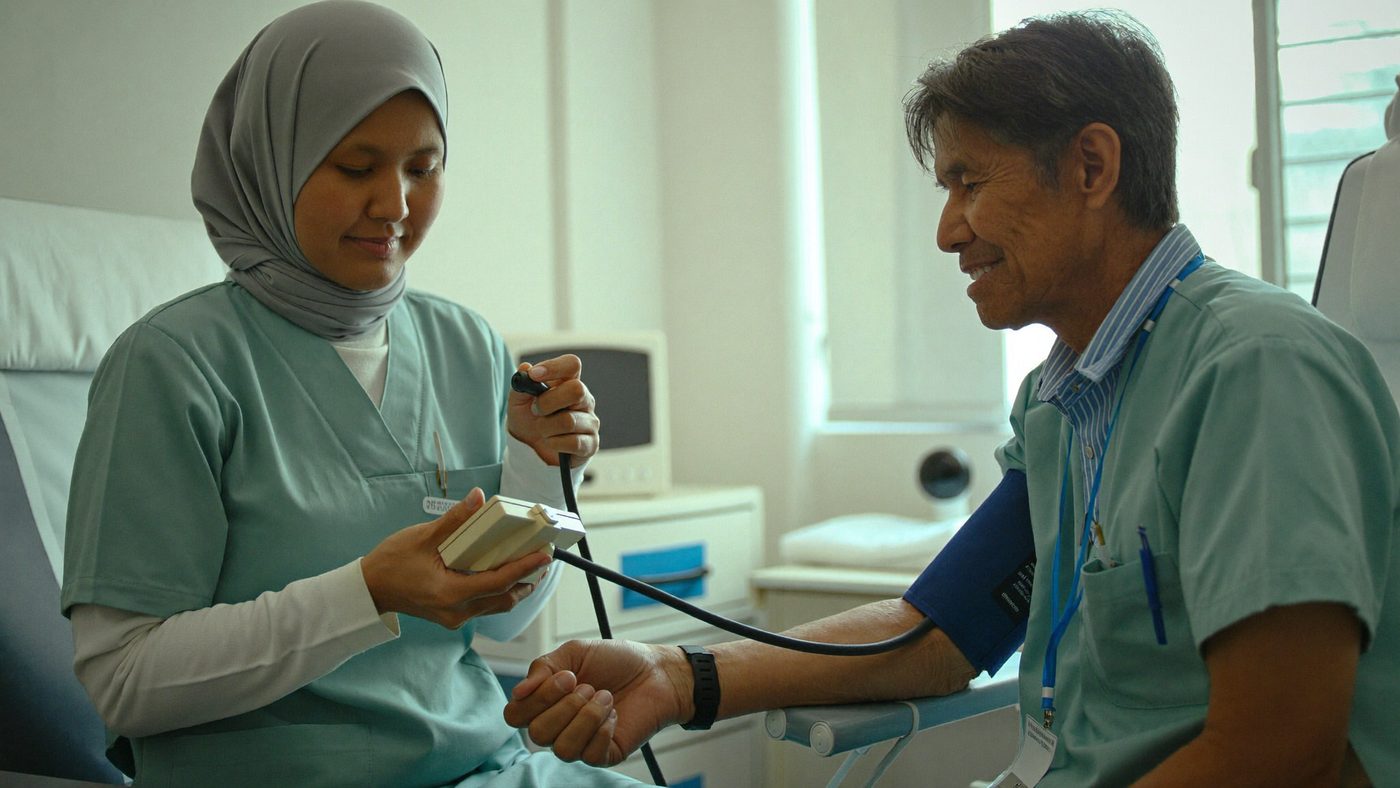 Perawat mengukur tekanan darah pasien lanjut usia di ruang periksa